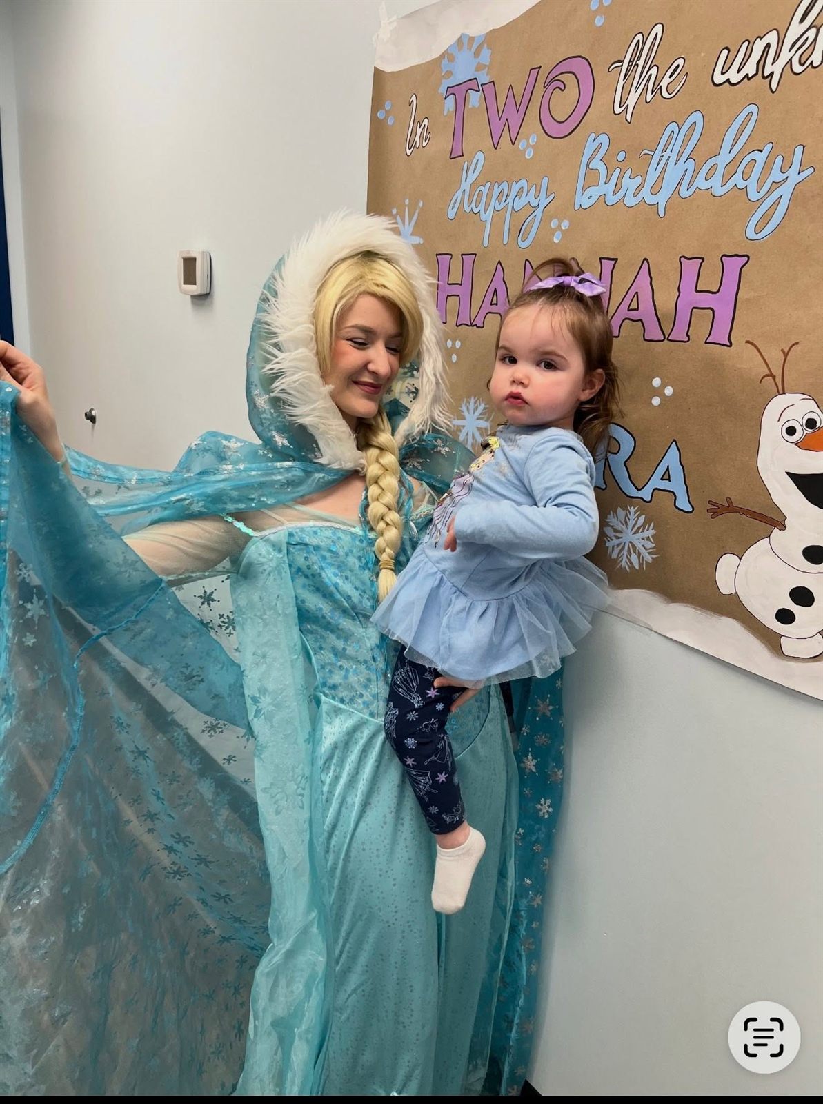 Ice-queen princess character in a blue gown holding a toddler at a winter-themed 2nd birthday party
