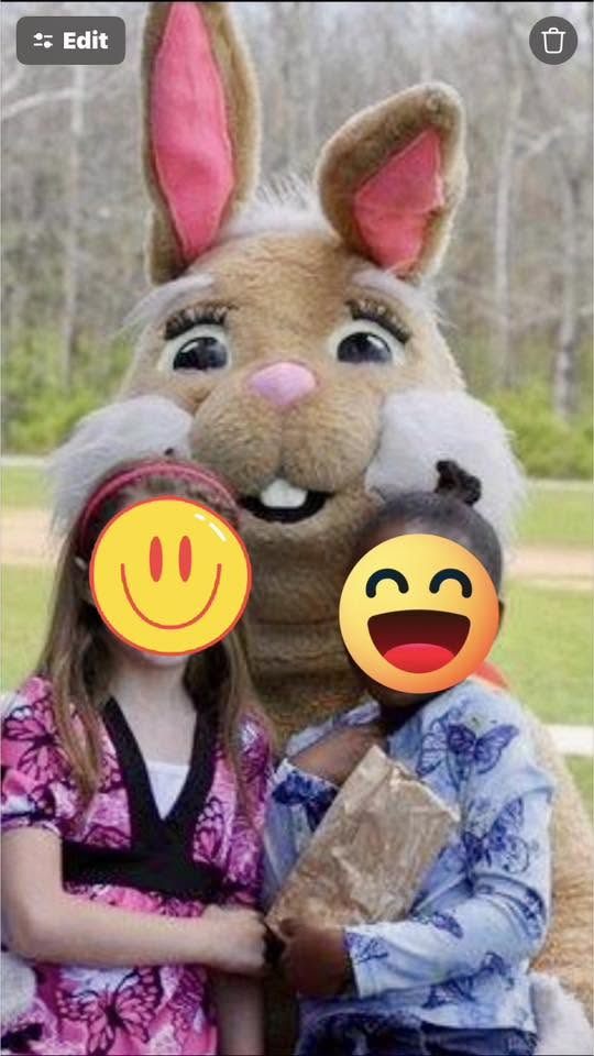 A costumed bunny mascot performer posing with two smiling children outdoors at a spring event