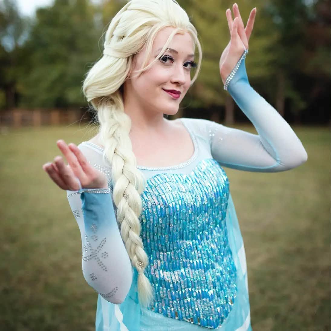 Ice-queen princess character in a sparkling blue gown and braid posing outdoors in a park