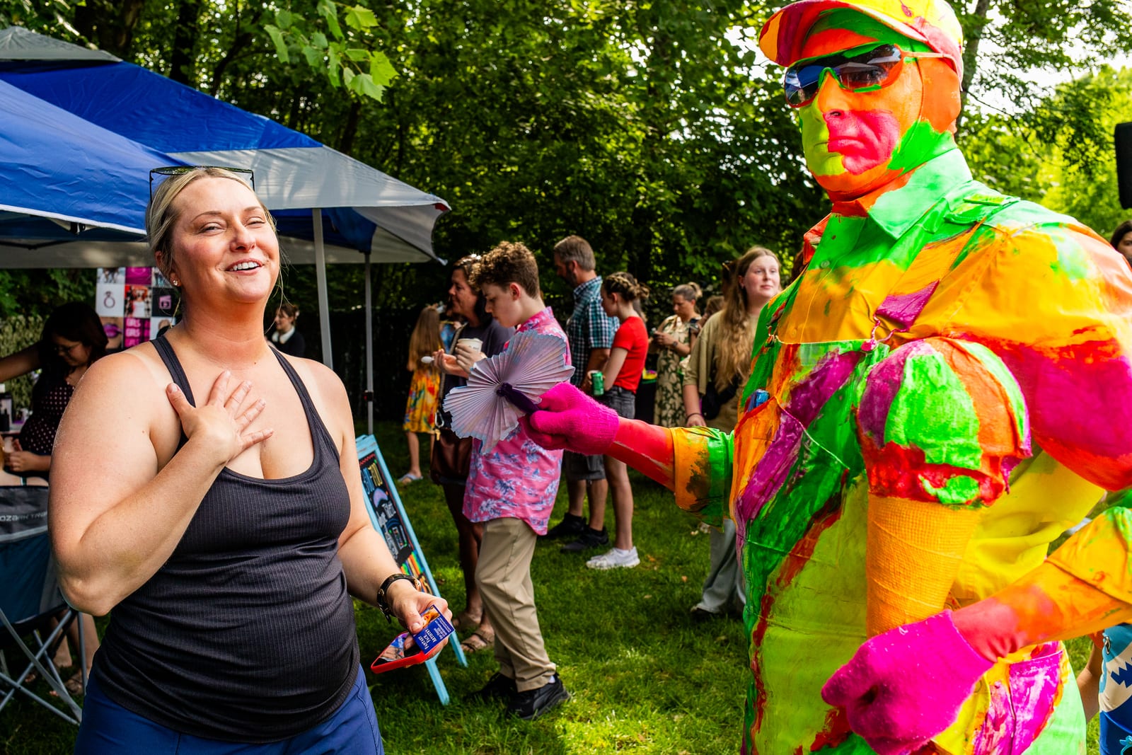 Guest reacting with delight to a neon-costumed performer at an outdoor party