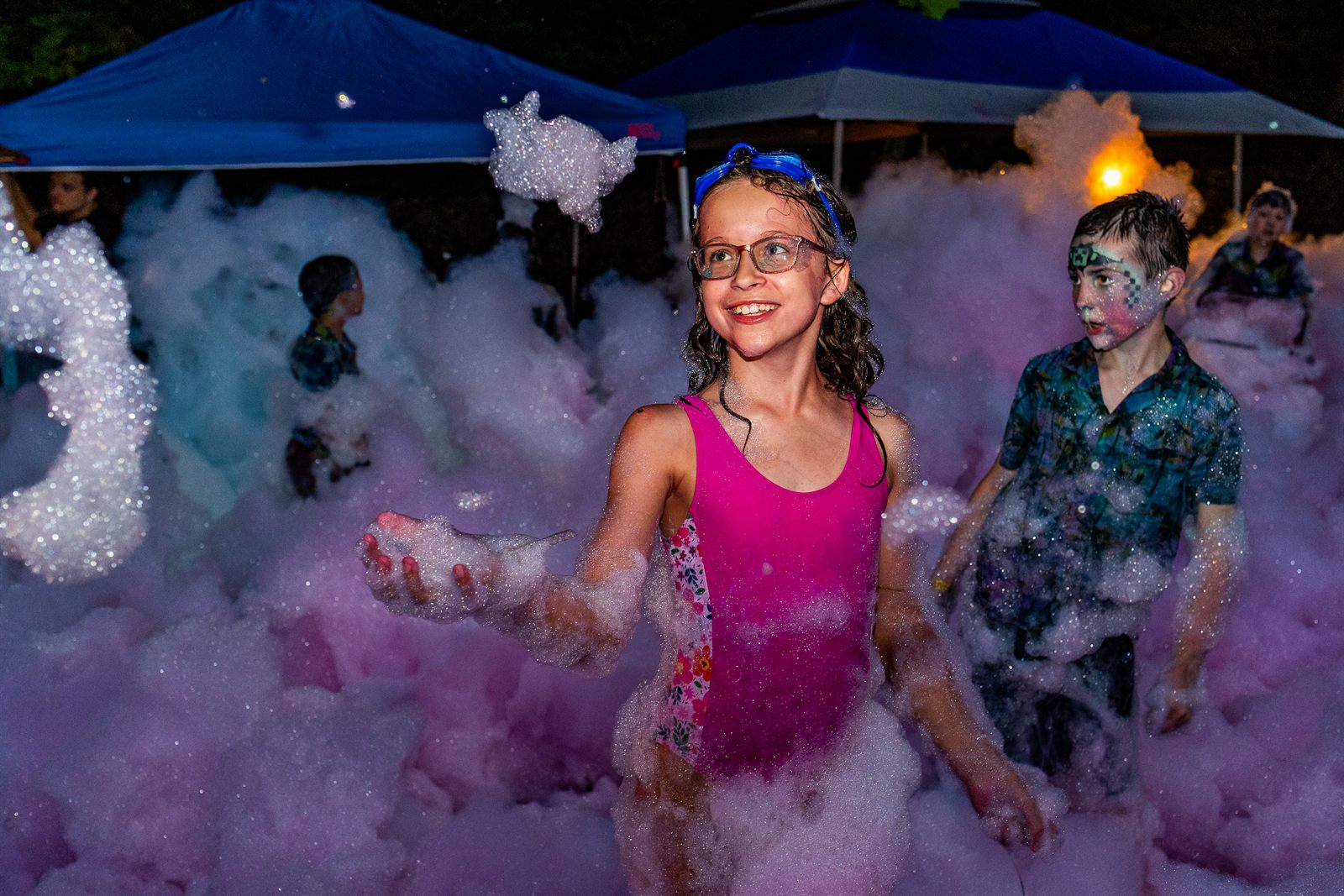 Children in colorful mermaid tails playing in a water feature surrounded by bright décor