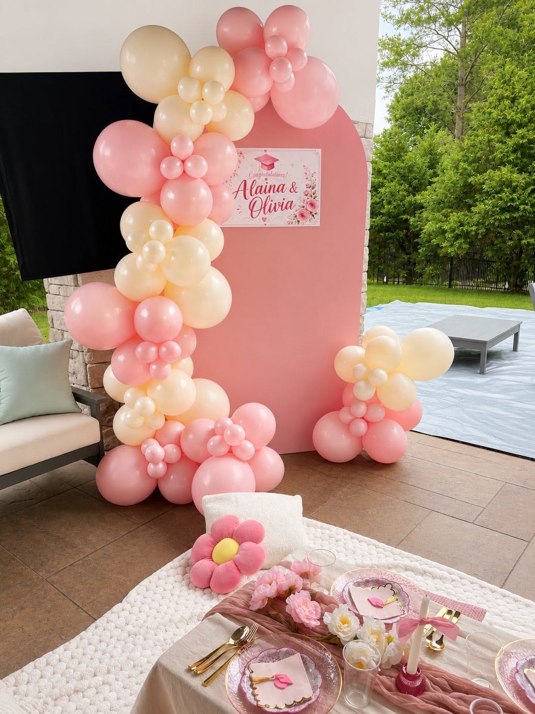 Blush and cream balloon garland framing a pink arch backdrop with a personalised sign and dessert table