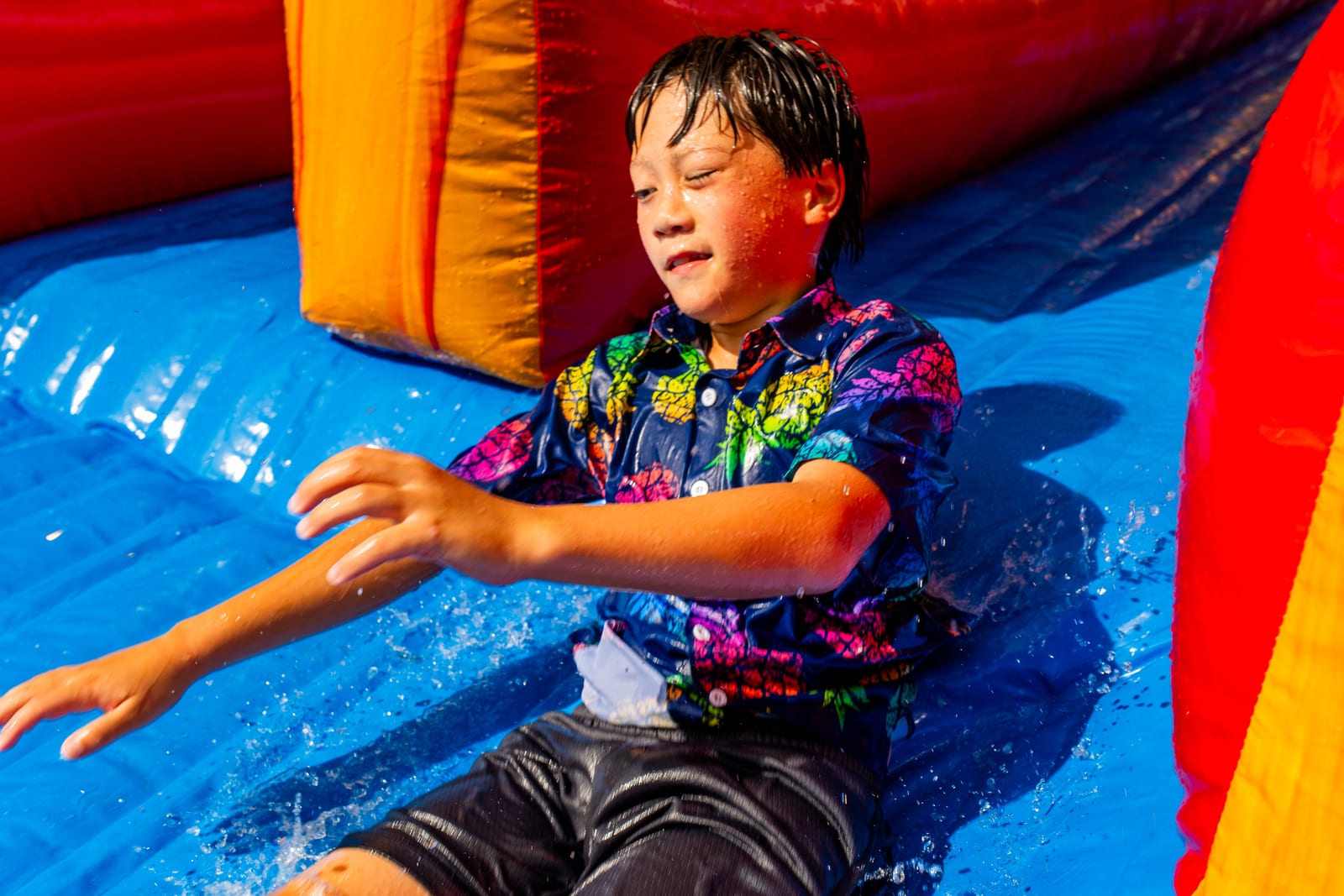 Child sliding down a wet inflatable slide into a splash pool