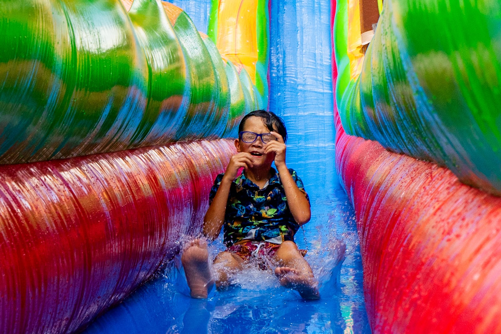 Child riding down a tall rainbow inflatable water slide
