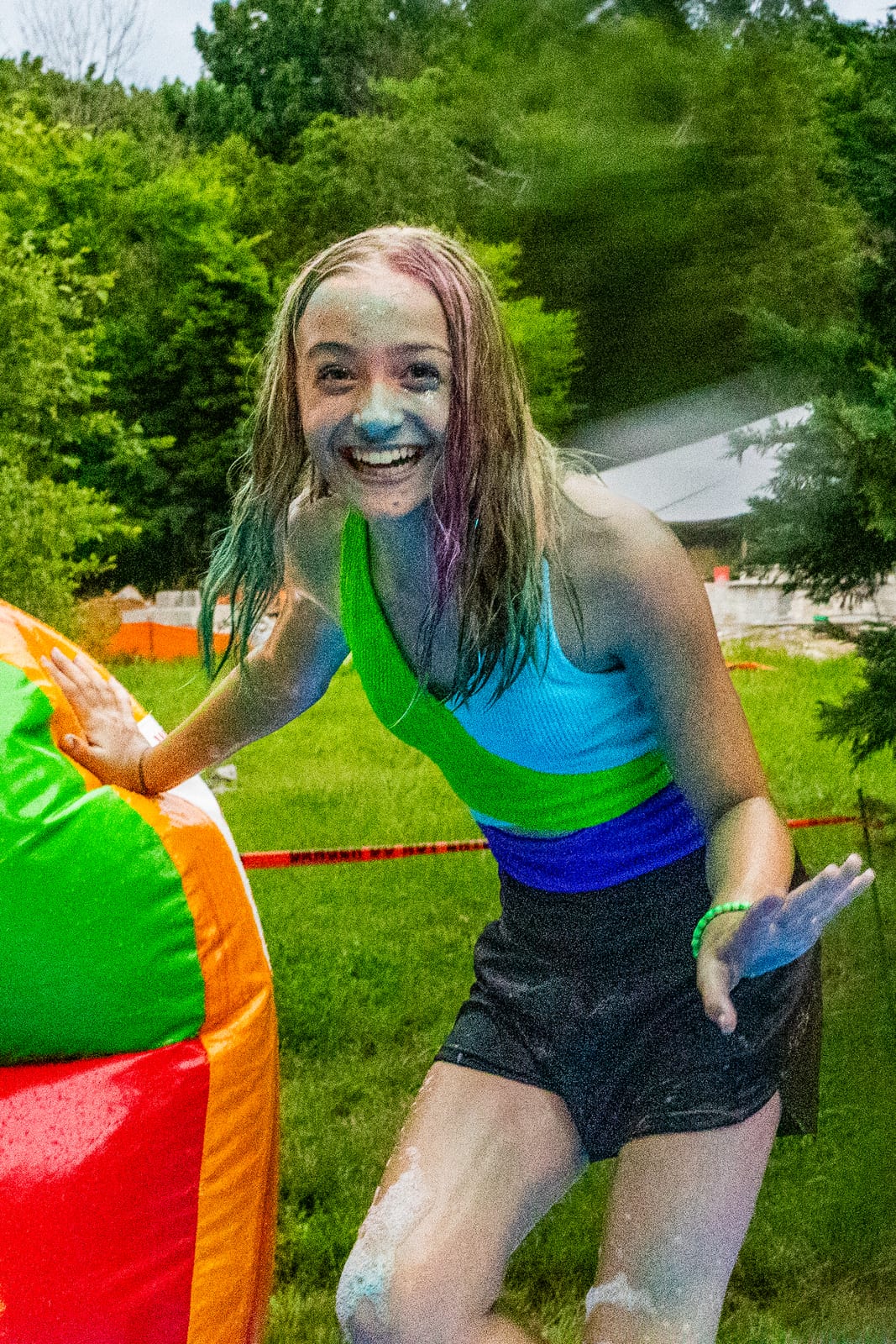 Guest laughing covered in foam beside a colorful inflatable