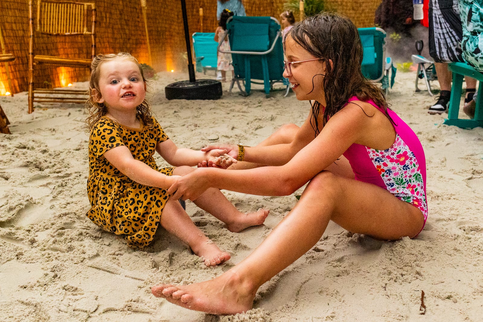 Two young guests sitting and playing together in a sand play area