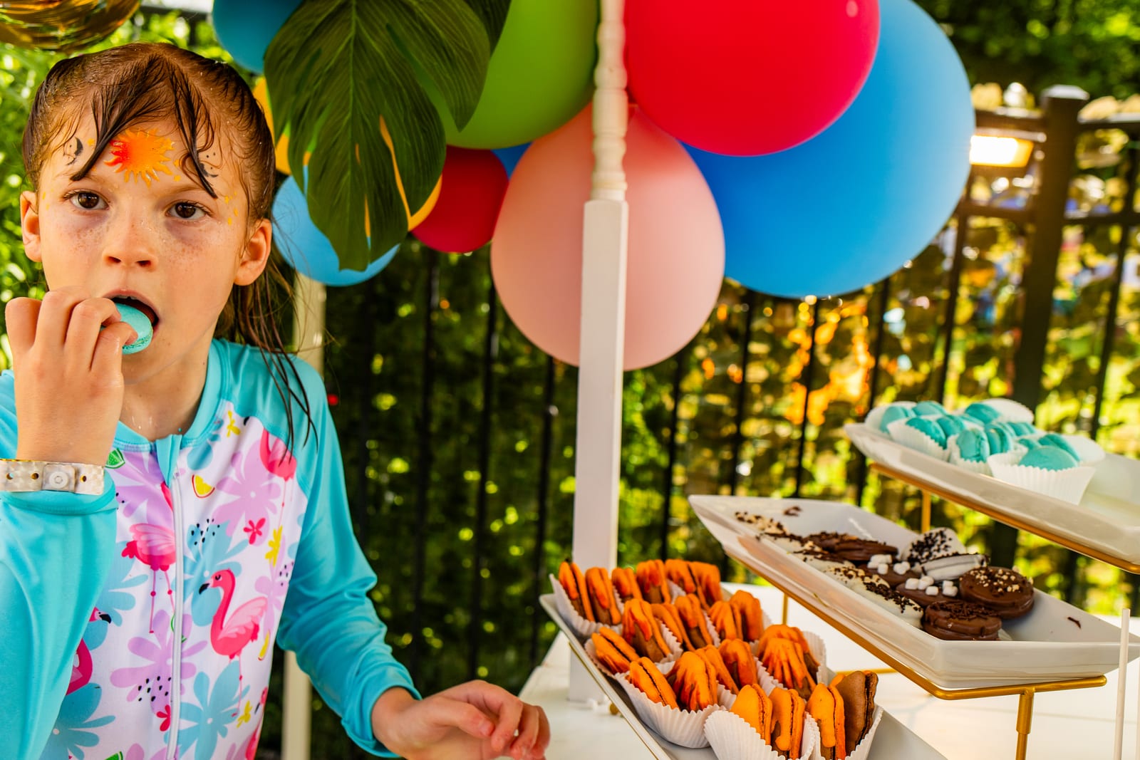 Young guest choosing a treat from a dessert table framed by balloons