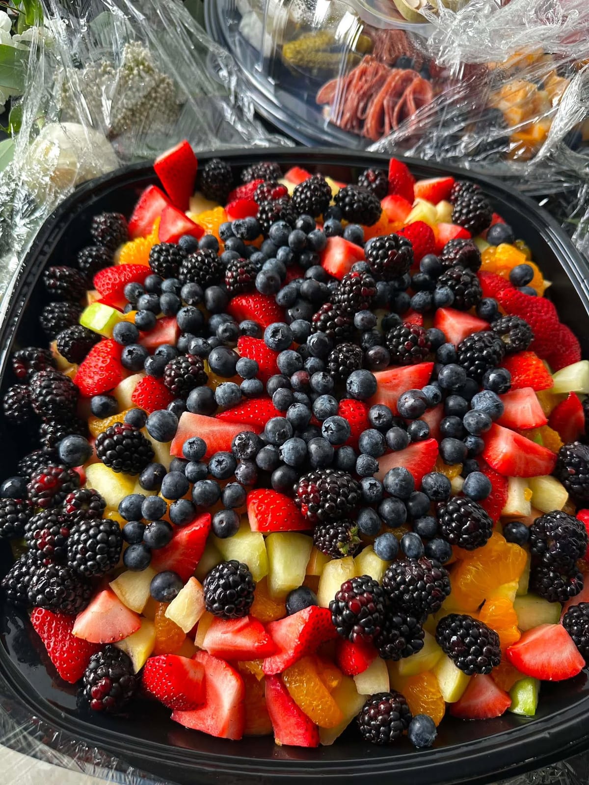 Round platter piled with strawberries, blackberries, blueberries and melon