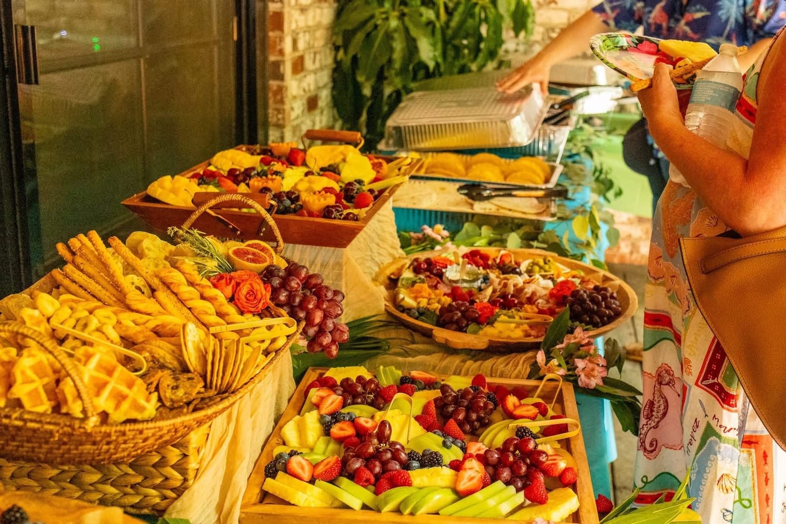 Long outdoor buffet lined with grazing boards of cheeses, crackers, fruit and vegetables