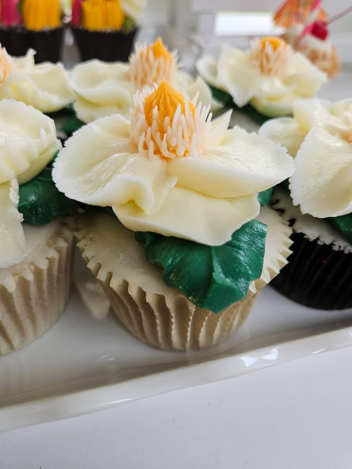 Close-up of cupcakes piped with white buttercream flowers and green leaves