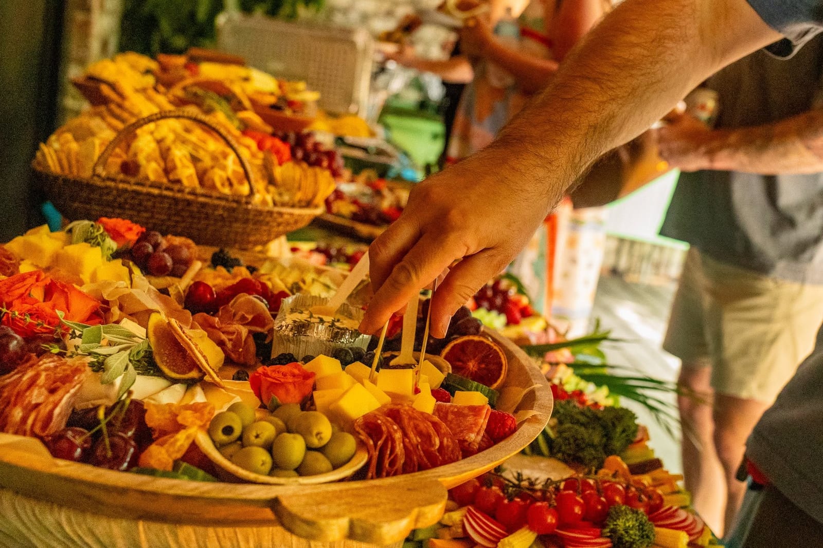 Large round grazing board of cured meats, cheeses, olives, breads and fruit on an outdoor table