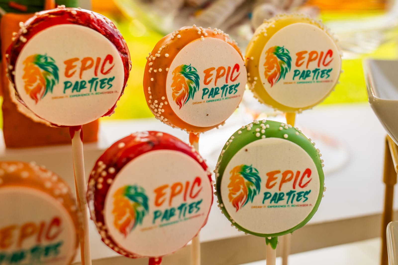 Round cookie lollipops iced in red, orange and green with the EPIC Parties lion logo