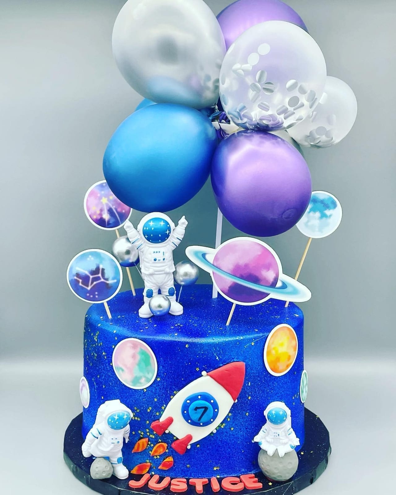 Deep blue space-themed birthday cake with planets, a rocket and an astronaut topper