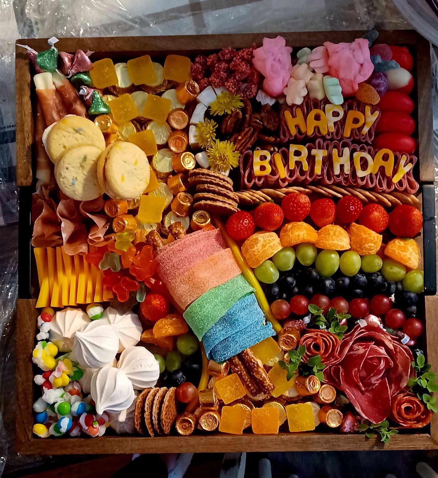Large wooden grazing board of sweets, fruit, cheeses and a Happy Birthday sign