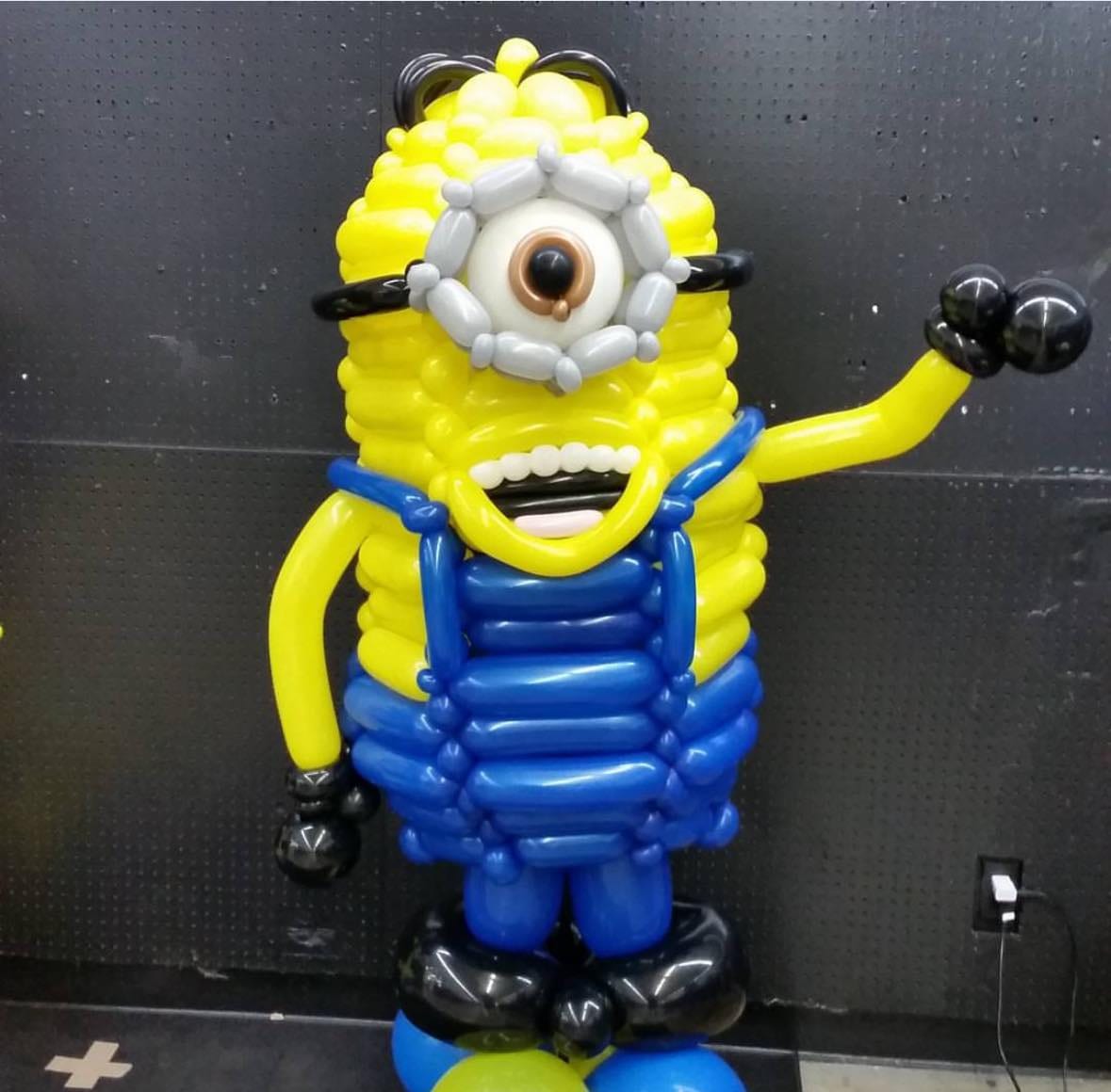 Balloon sculpture of a yellow one-eyed cartoon character standing over a metre tall