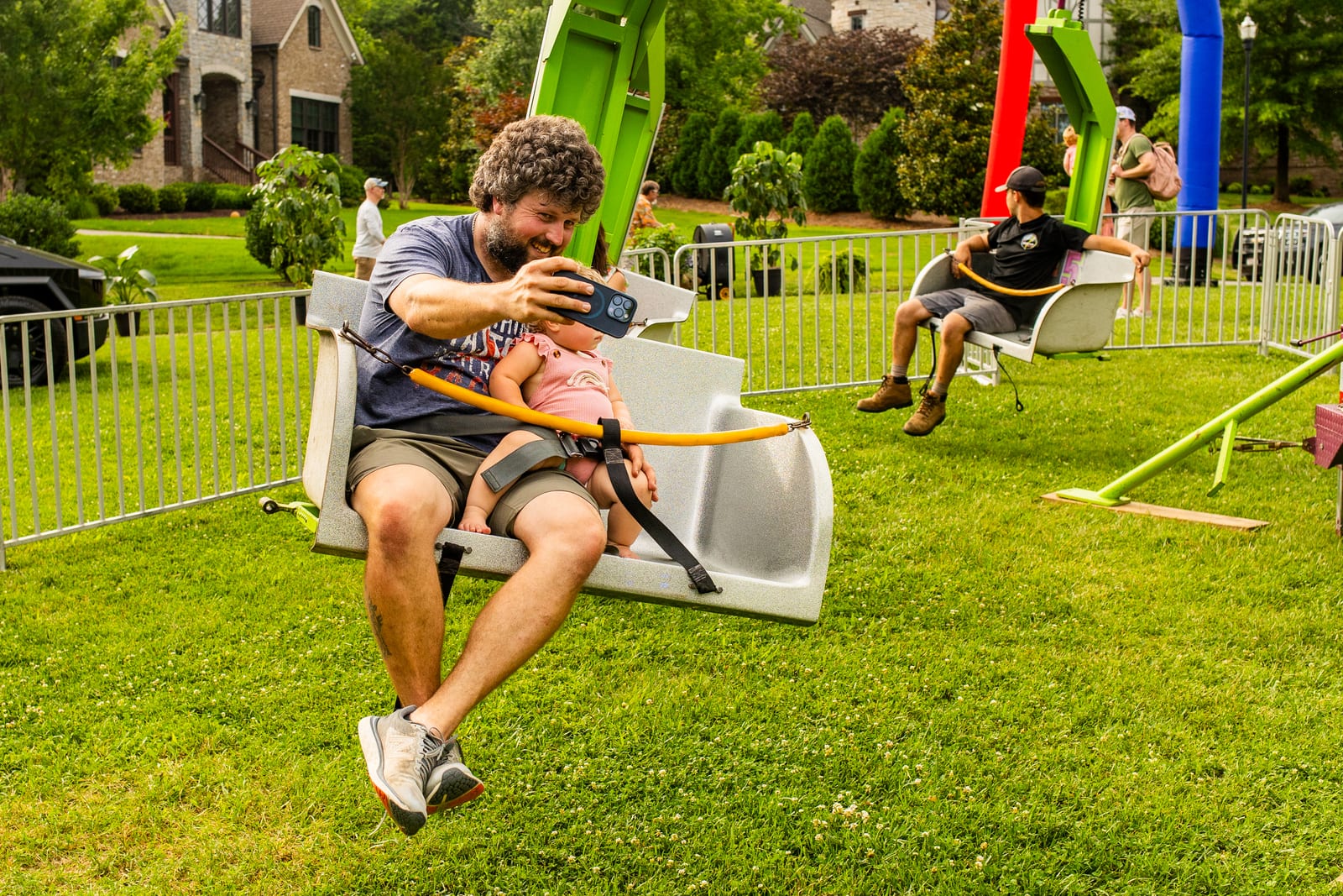 An adult and child riding a swing ride together on a lawn
