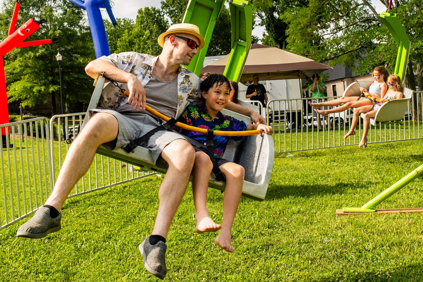 Adult and child seated together on a swing ride at a garden party