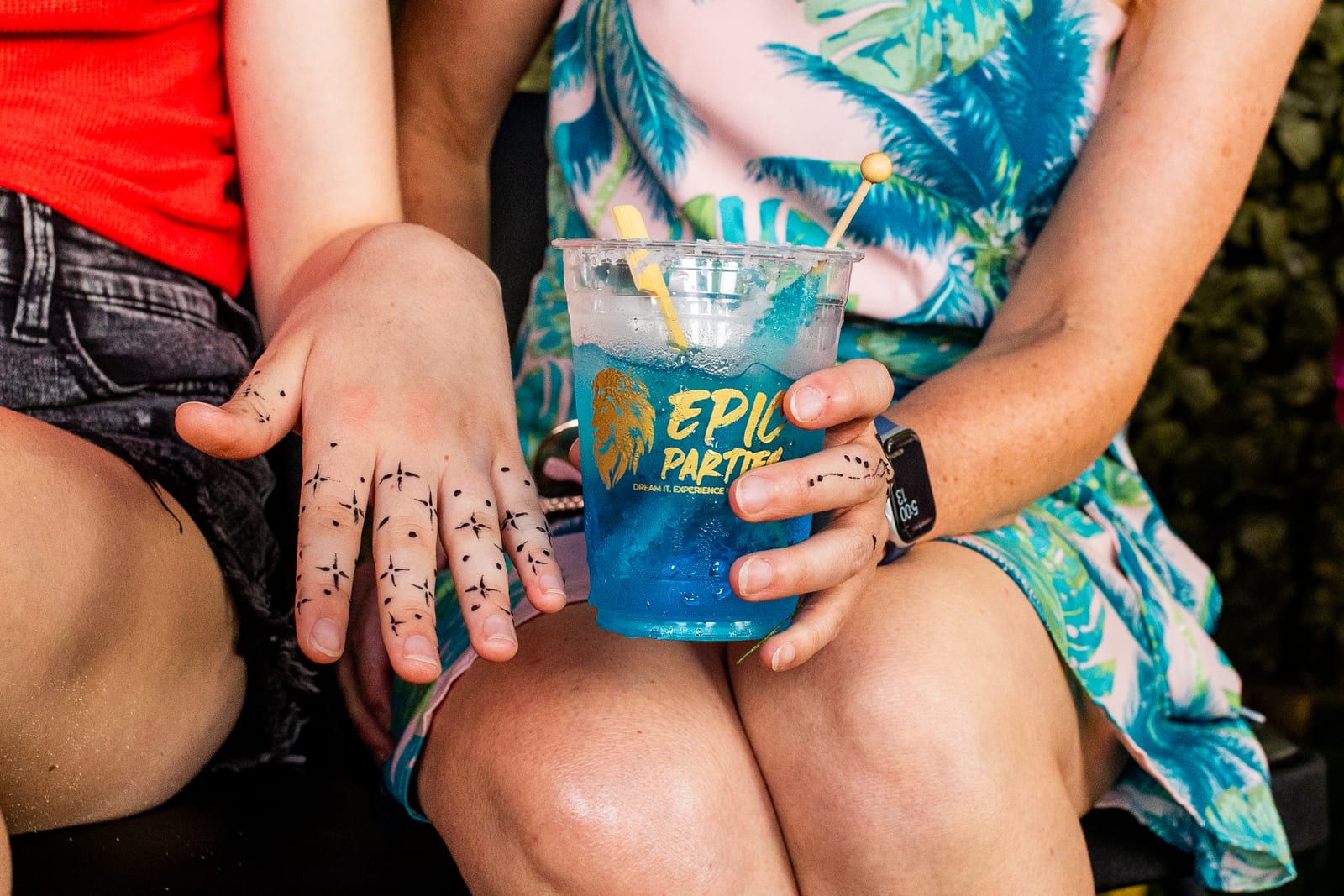 Guest showing hands decorated with fine line art while holding a branded party cup