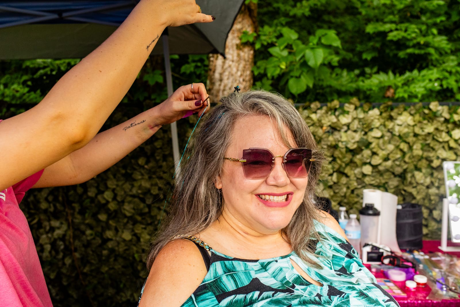 Guest smiling as hair tinsel is added at an outdoor styling station