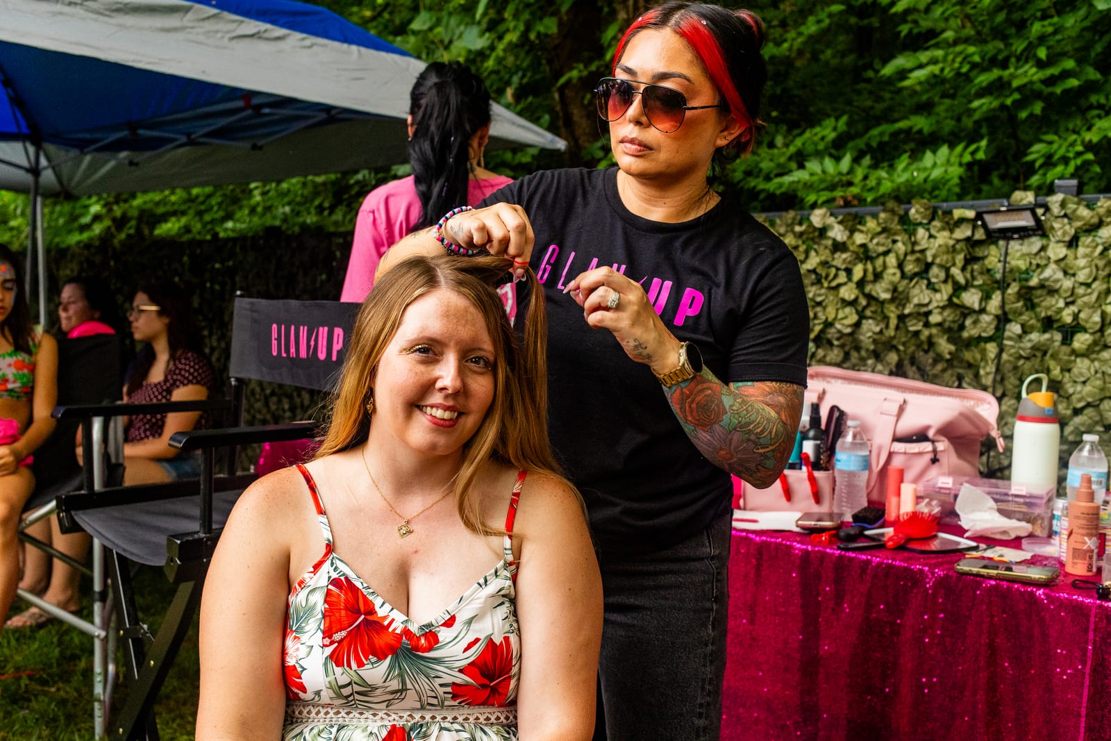 Guest having her hair styled at an outdoor beauty station under a canopy