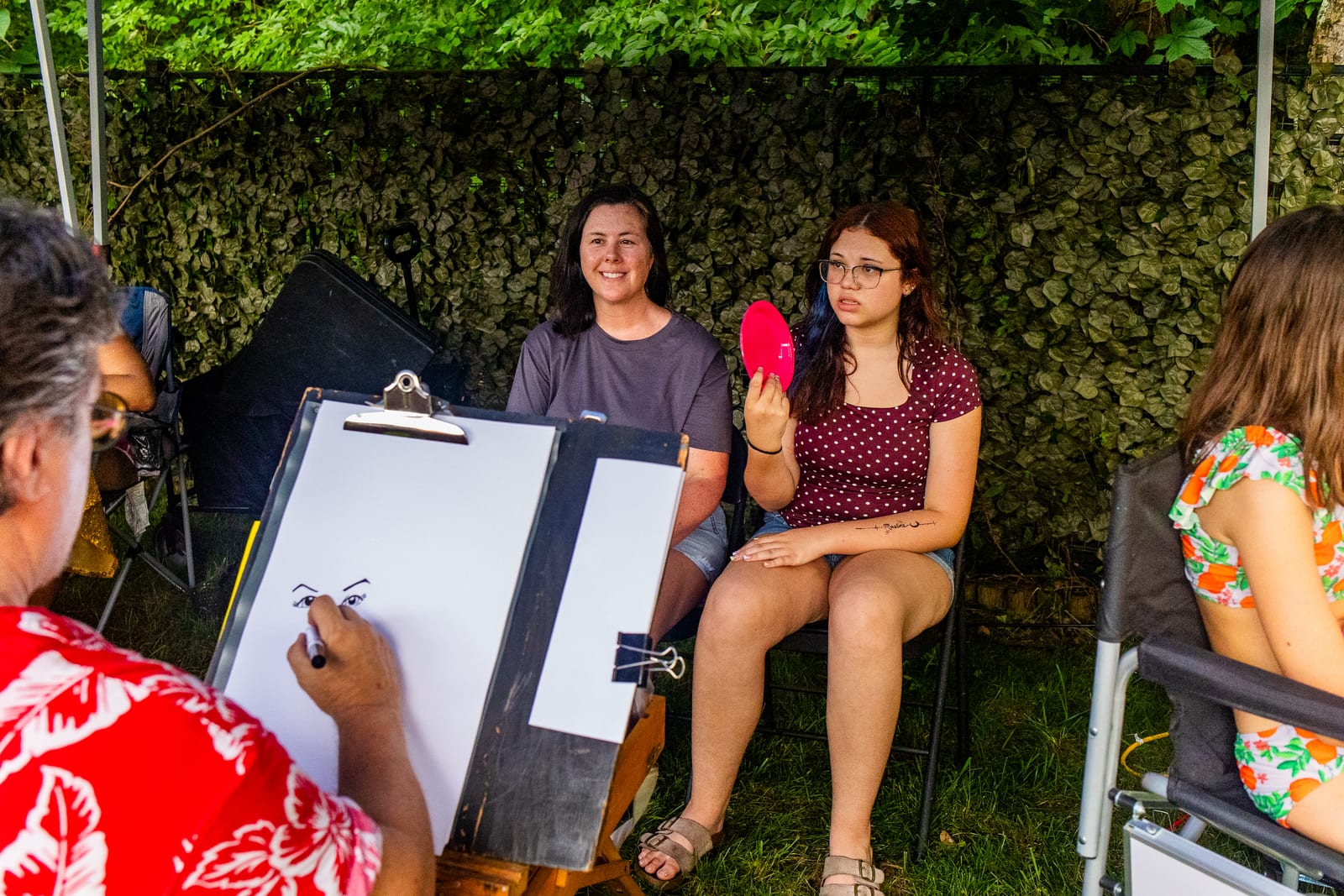 Caricature artist sketching seated guests at an outdoor easel