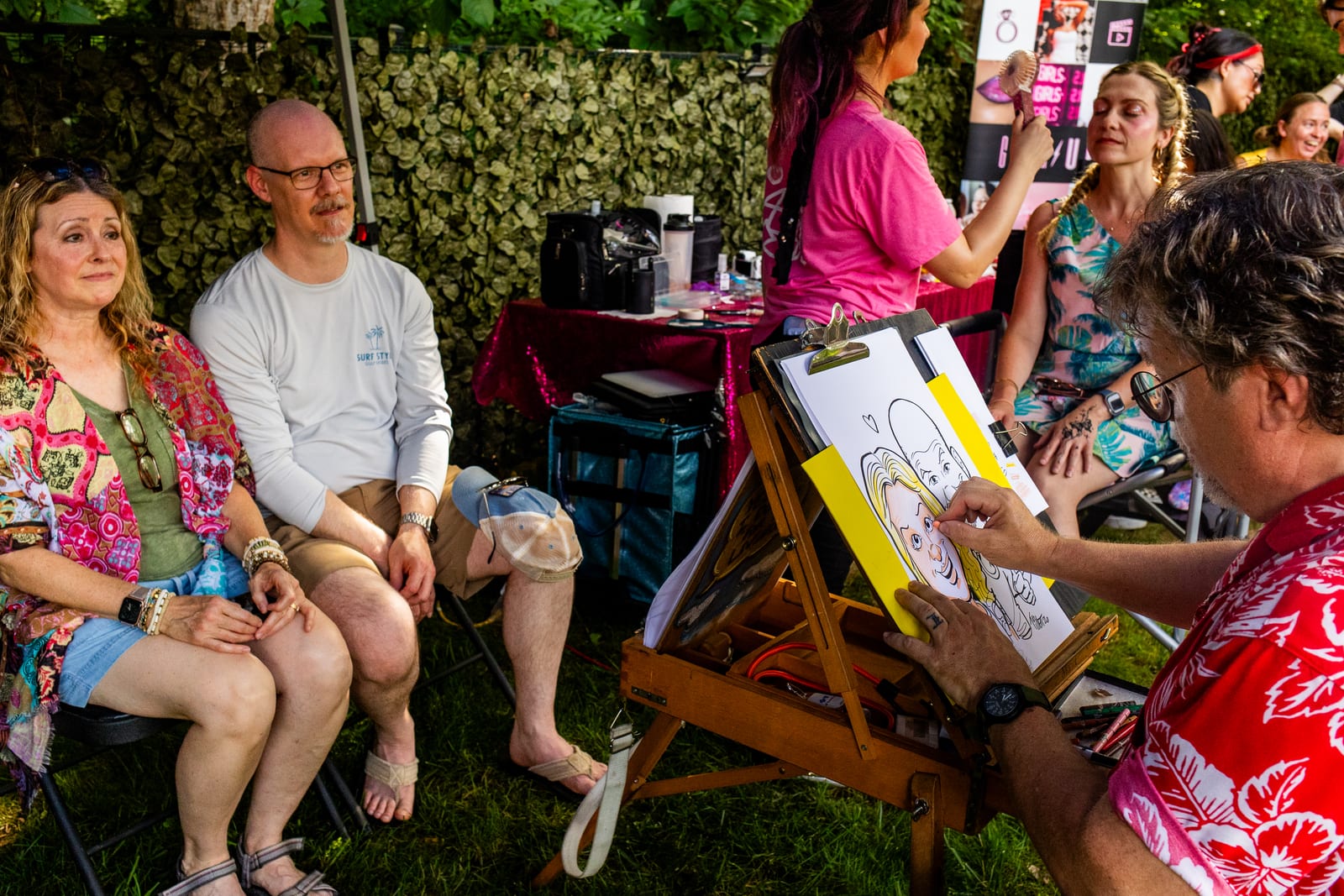 Caricature artist drawing guests seated in a shaded garden area