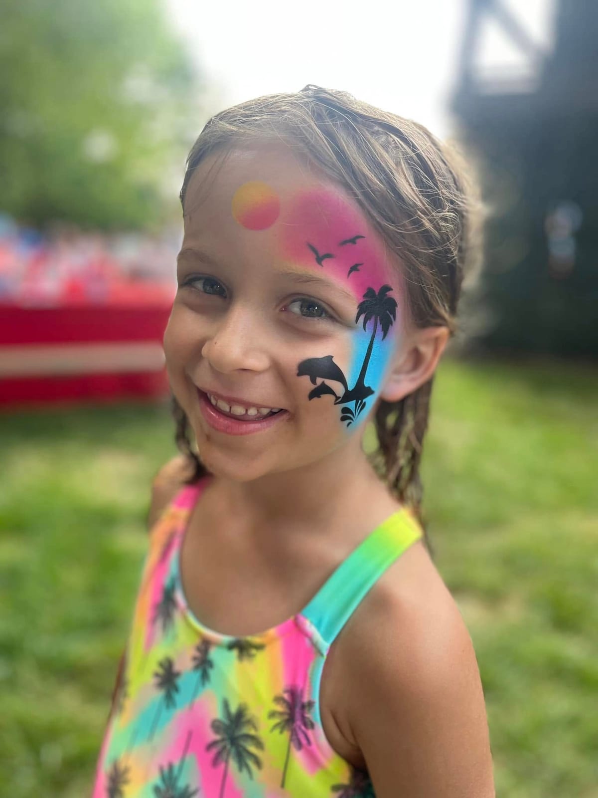 Young guest with butterfly and star face paint smiling on a lawn