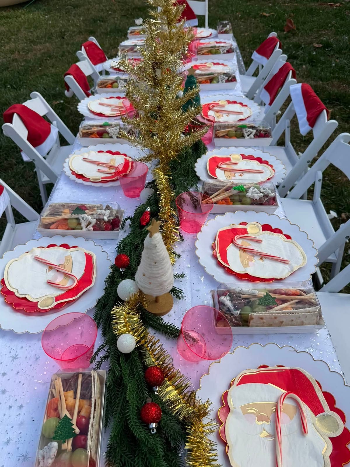 Long Christmas dinner table set in red and white with a garland runner, crackers and gold accents. Holiday Parties by EPIC Parties in Middle Tennessee.