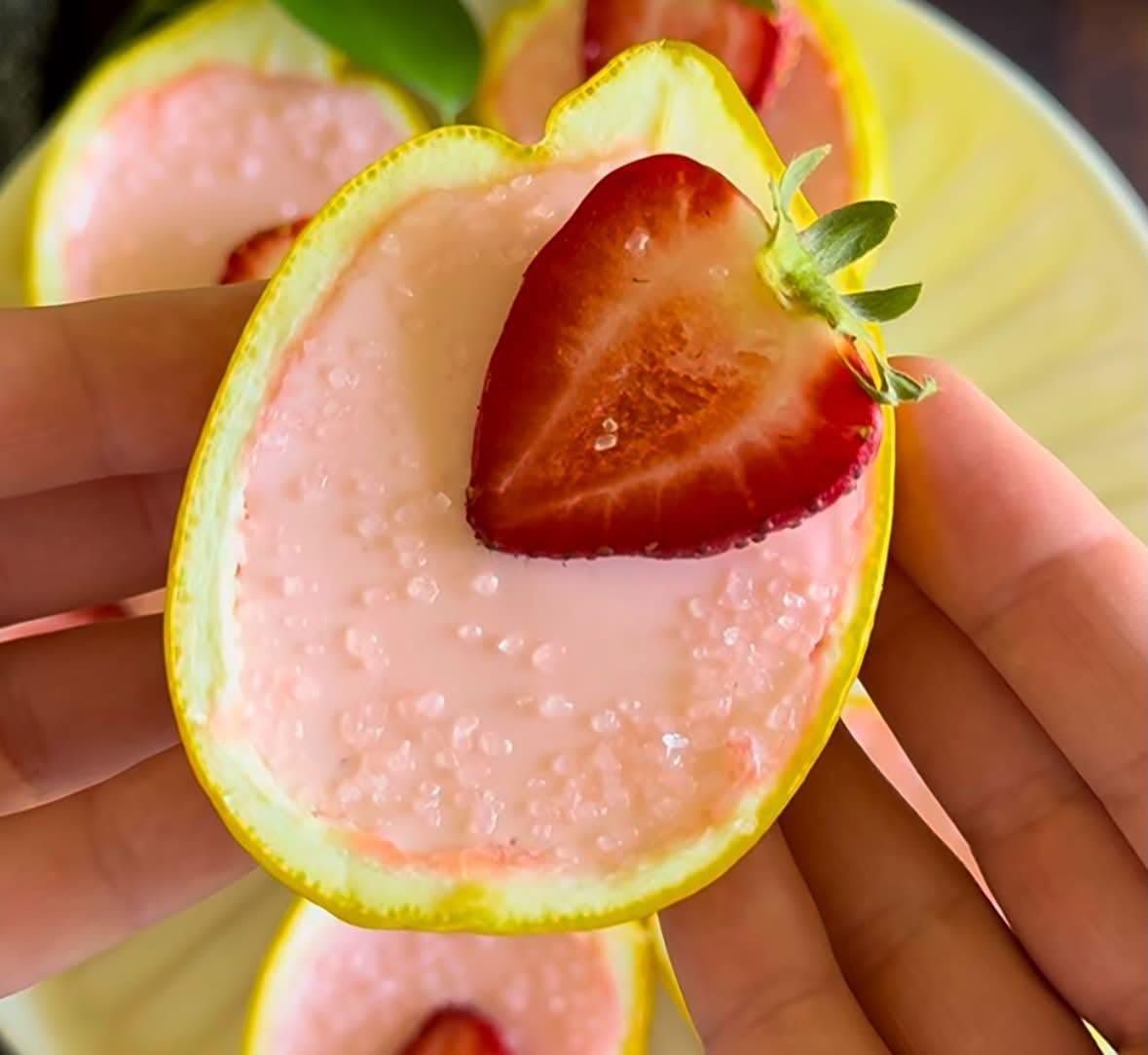 Lemon halves filled with pink strawberry cream, each topped with a fresh strawberry slice