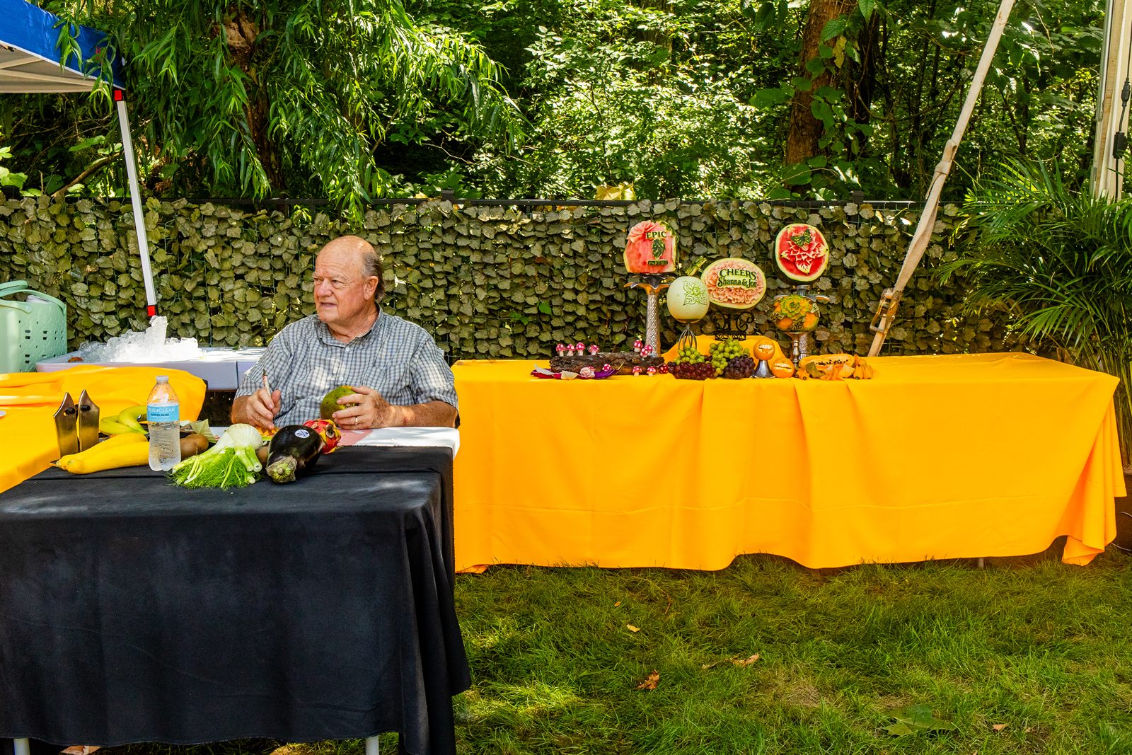 An elaborate tropical fruit-carving buffet on gold linen in a lush garden setting