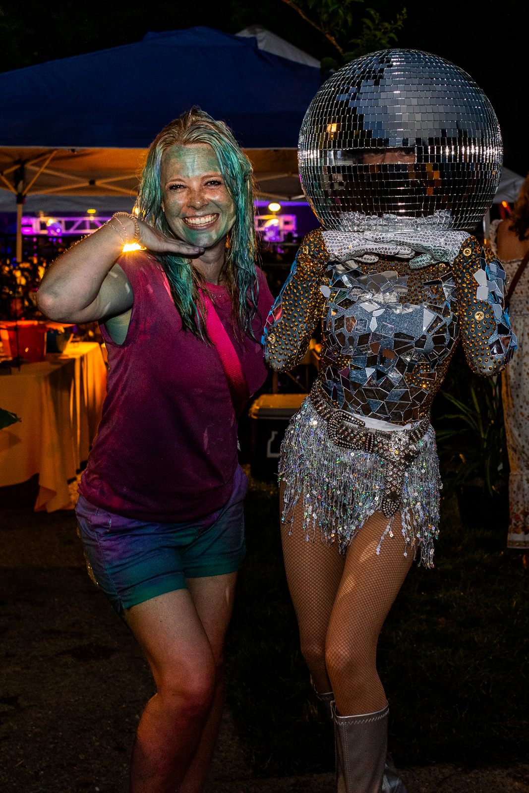 Guest poses beside a mirror-ball dancer in a full disco-ball head and mosaic mirror bodysuit at night