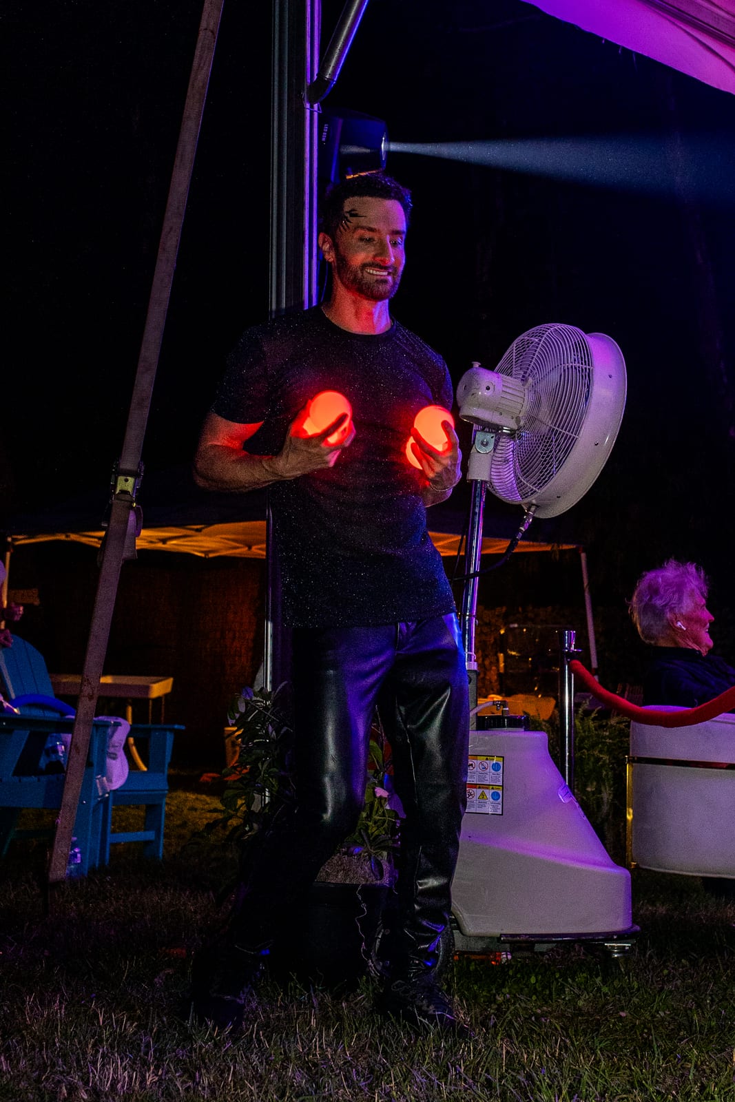 Performer holding two glowing orbs during a night-time light act