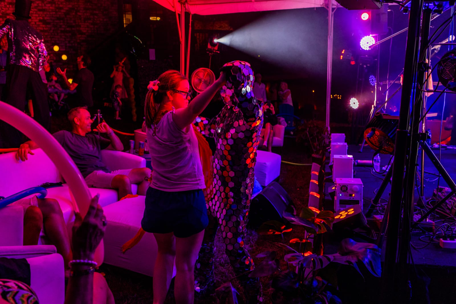 Guests dancing under saturated magenta and blue stage lighting at an outdoor party