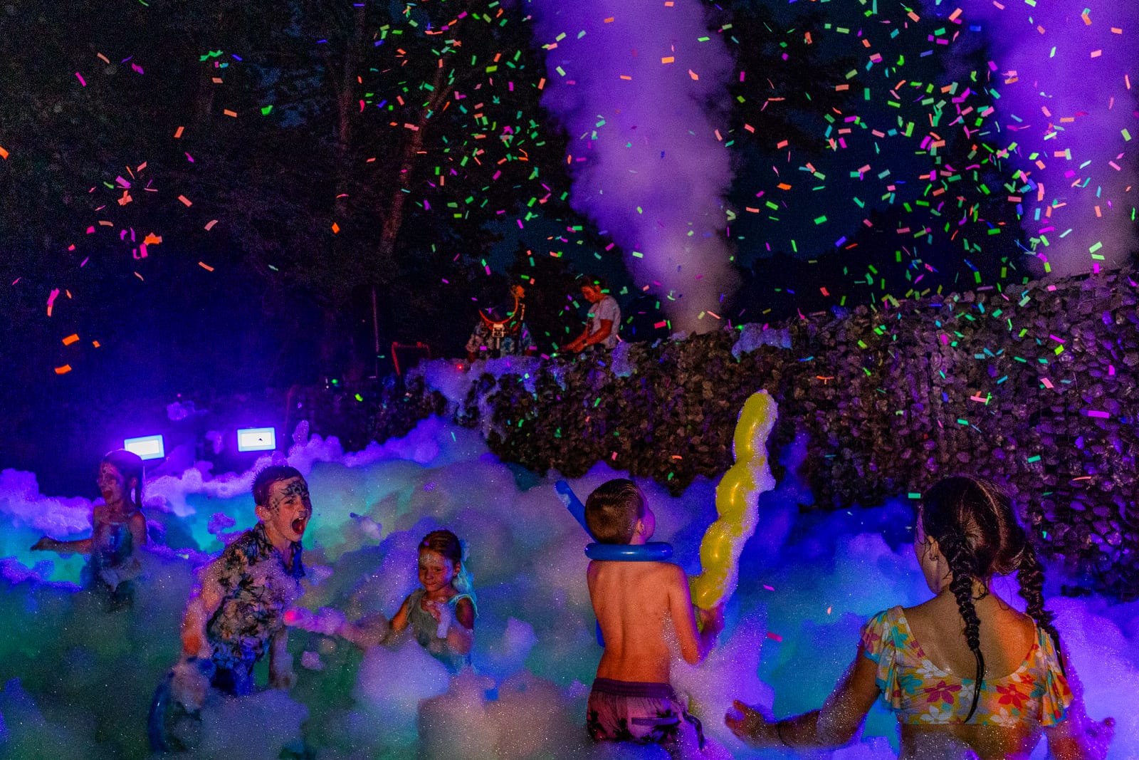 Blacklight foam party at night with neon confetti raining over the crowd