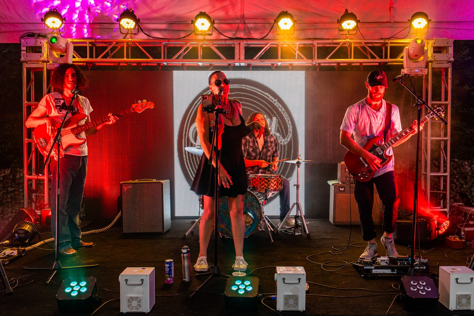 Live band performing on a truss stage under magenta and amber stage lighting