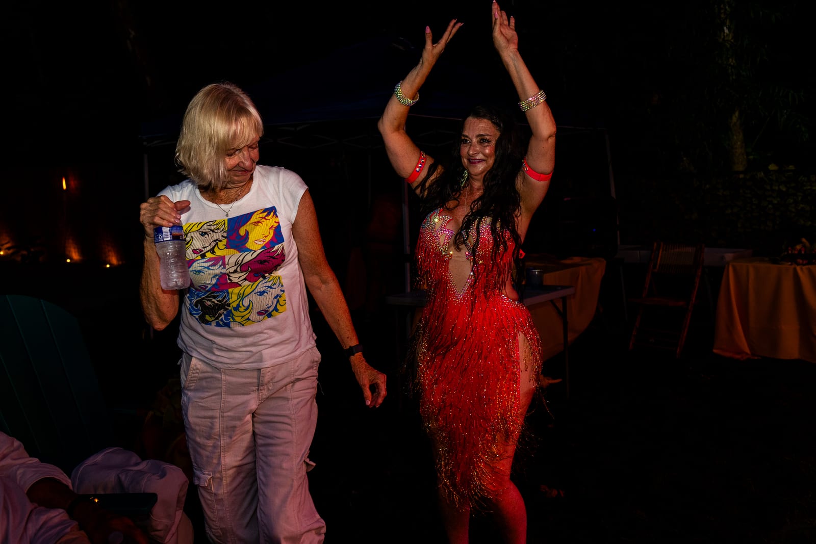 Guest dancing alongside a performer in a red fringed costume at night