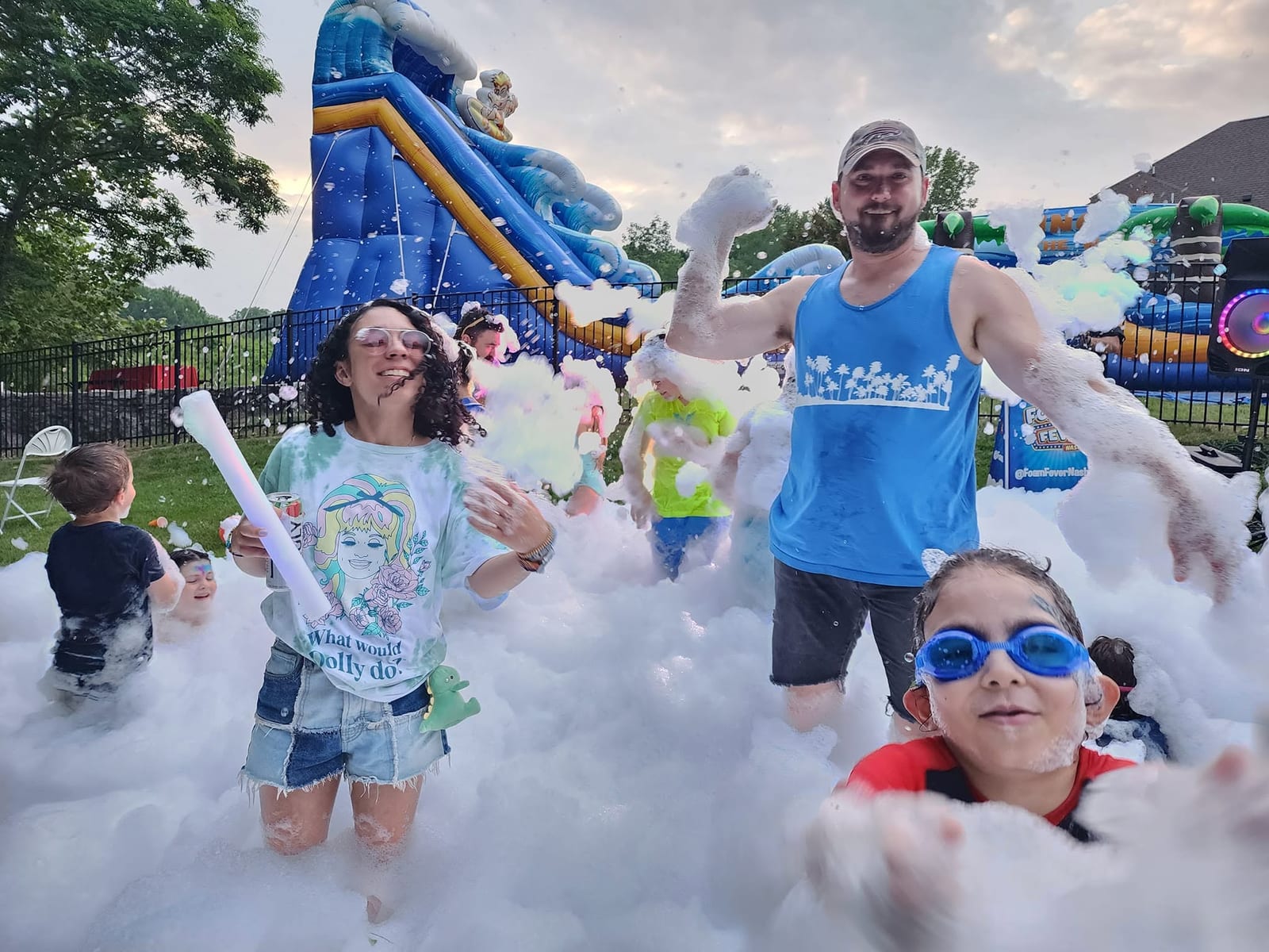 A family laughing together in white foam in front of an inflatable water slide