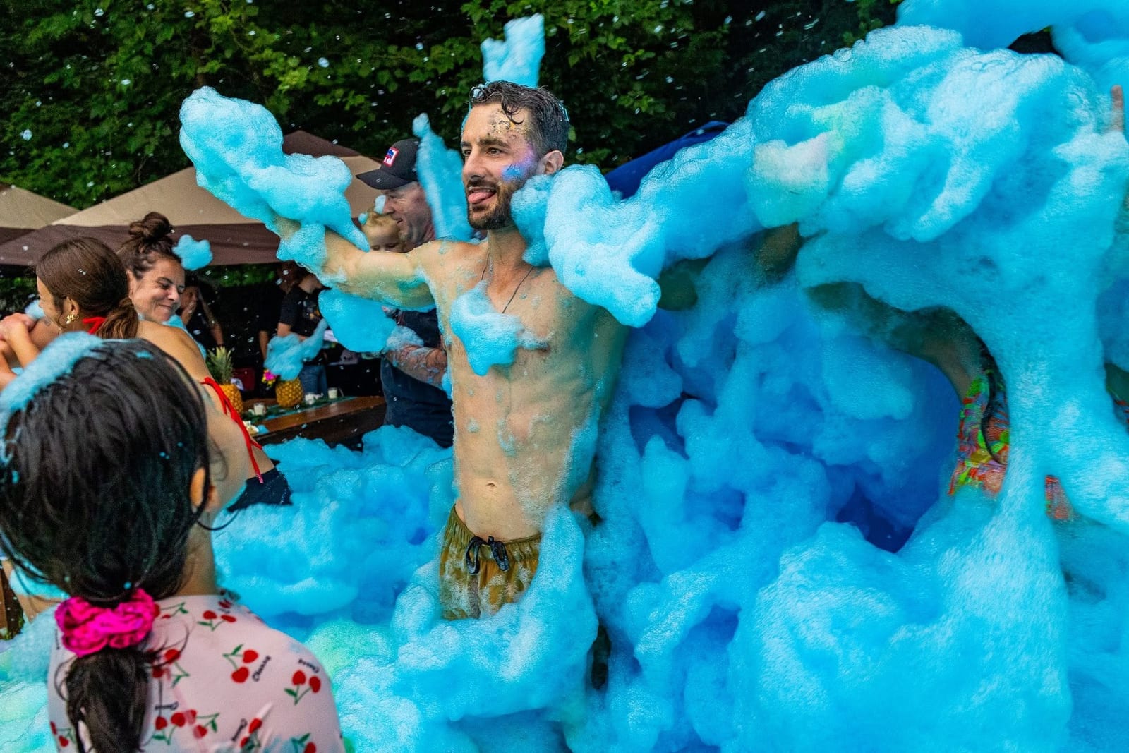 Guest standing arms outstretched covered in bright blue foam