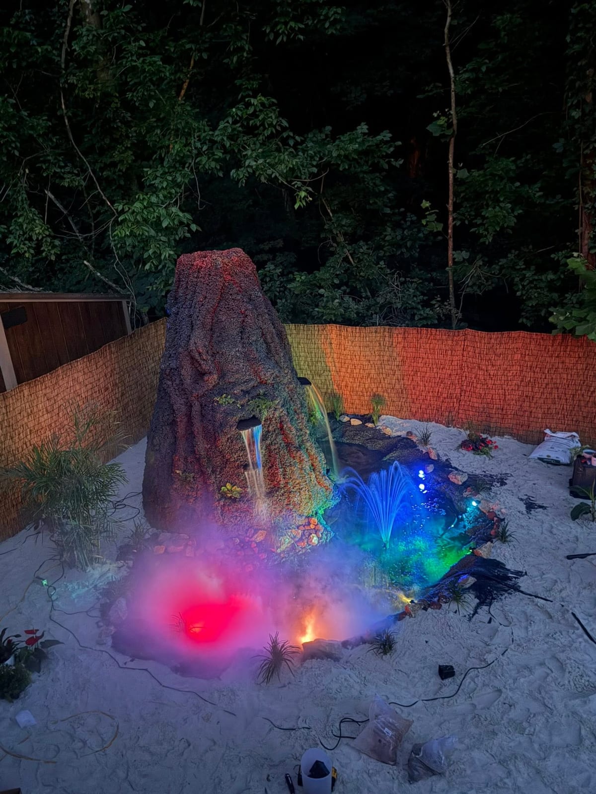 Illuminated volcano centrepiece glowing over a sand beach at night