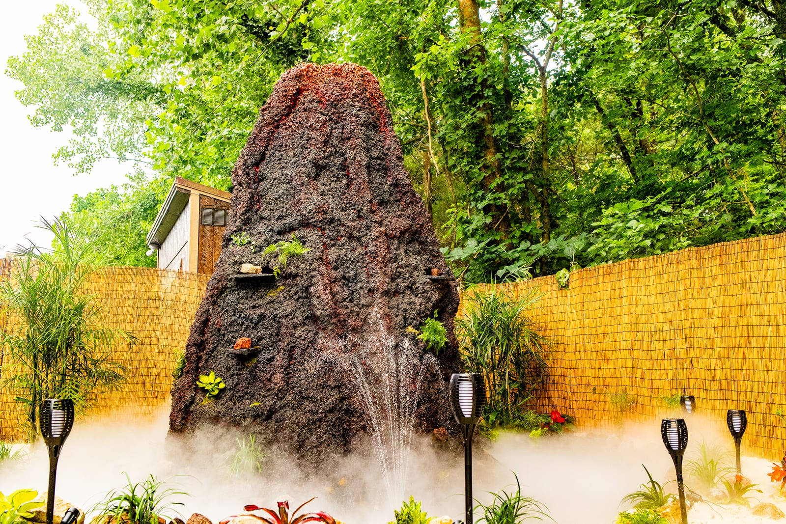 Large volcano centrepiece smoking over a sand beach beside torches in daylight