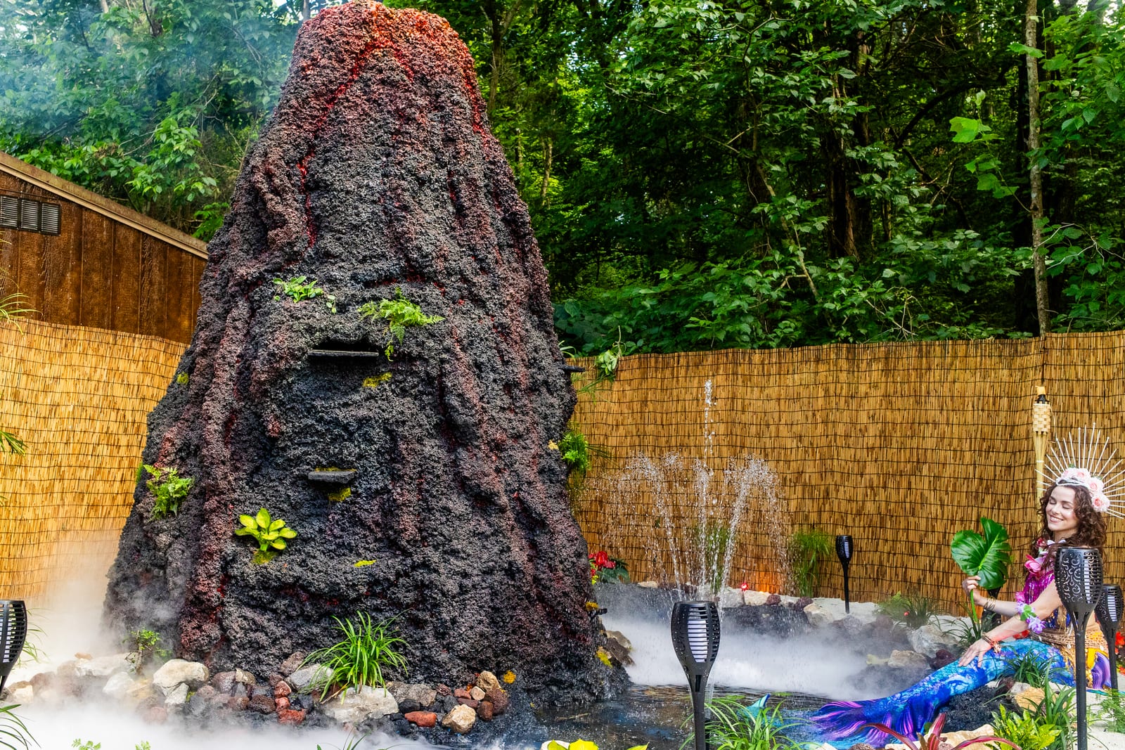 Volcano centrepiece with water features and costumed mermaid performers on a sand beach