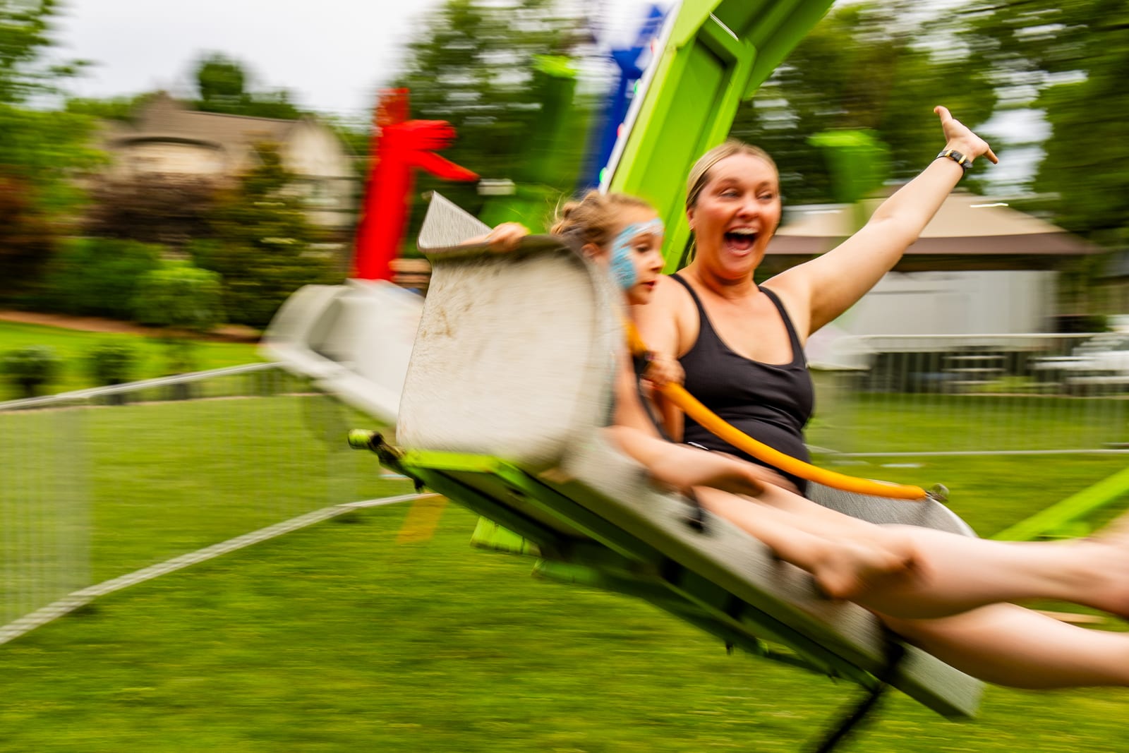 Guest flung outward on a fairground swing ride, arm raised, motion blurred