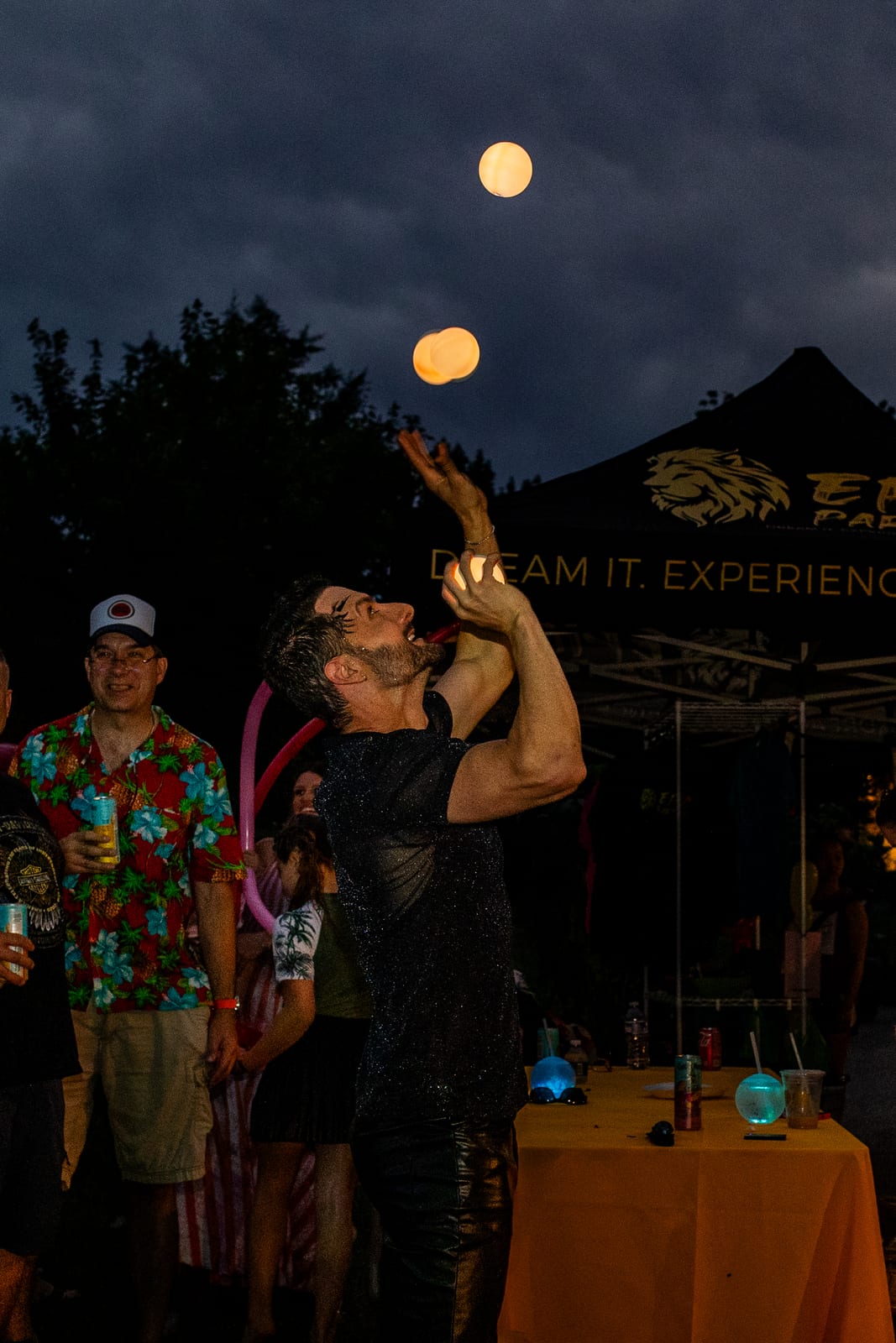 Fire performer holding a lit torch beside a guest under a full moon