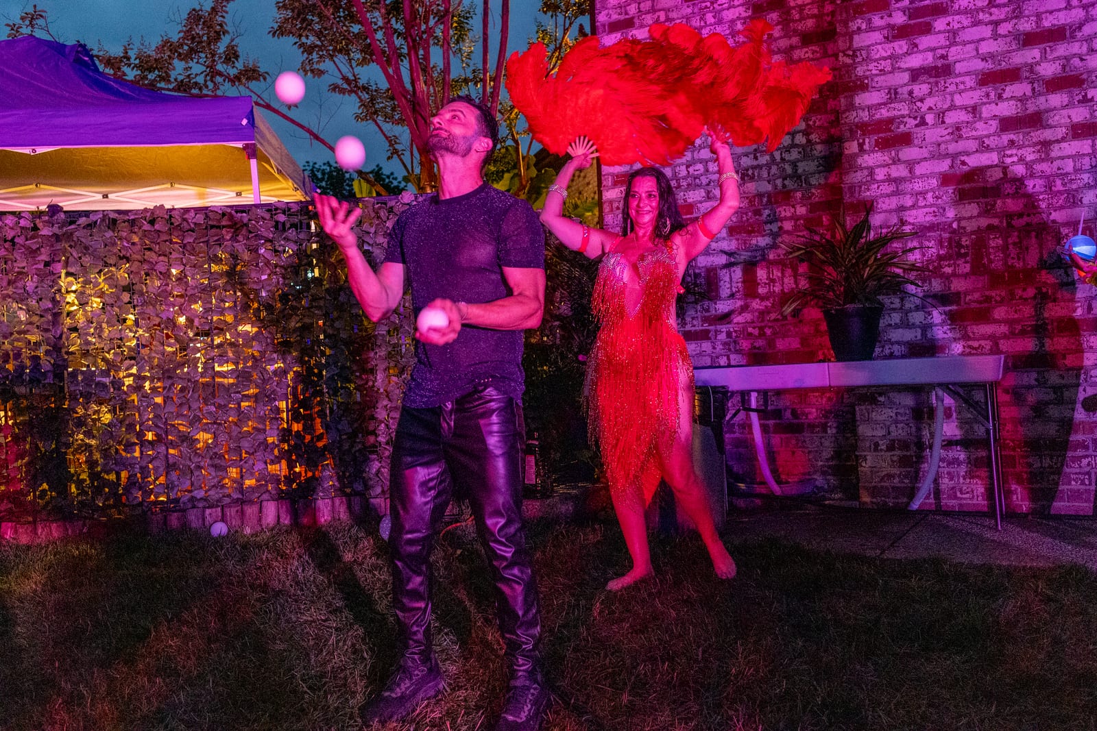 Juggler with glowing balls performing beside a dancer wreathed in red smoke