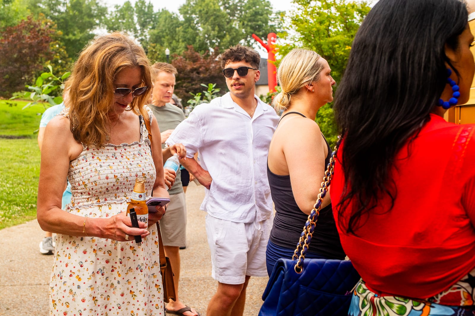 Guests mingling with drinks along a garden path at an outdoor party