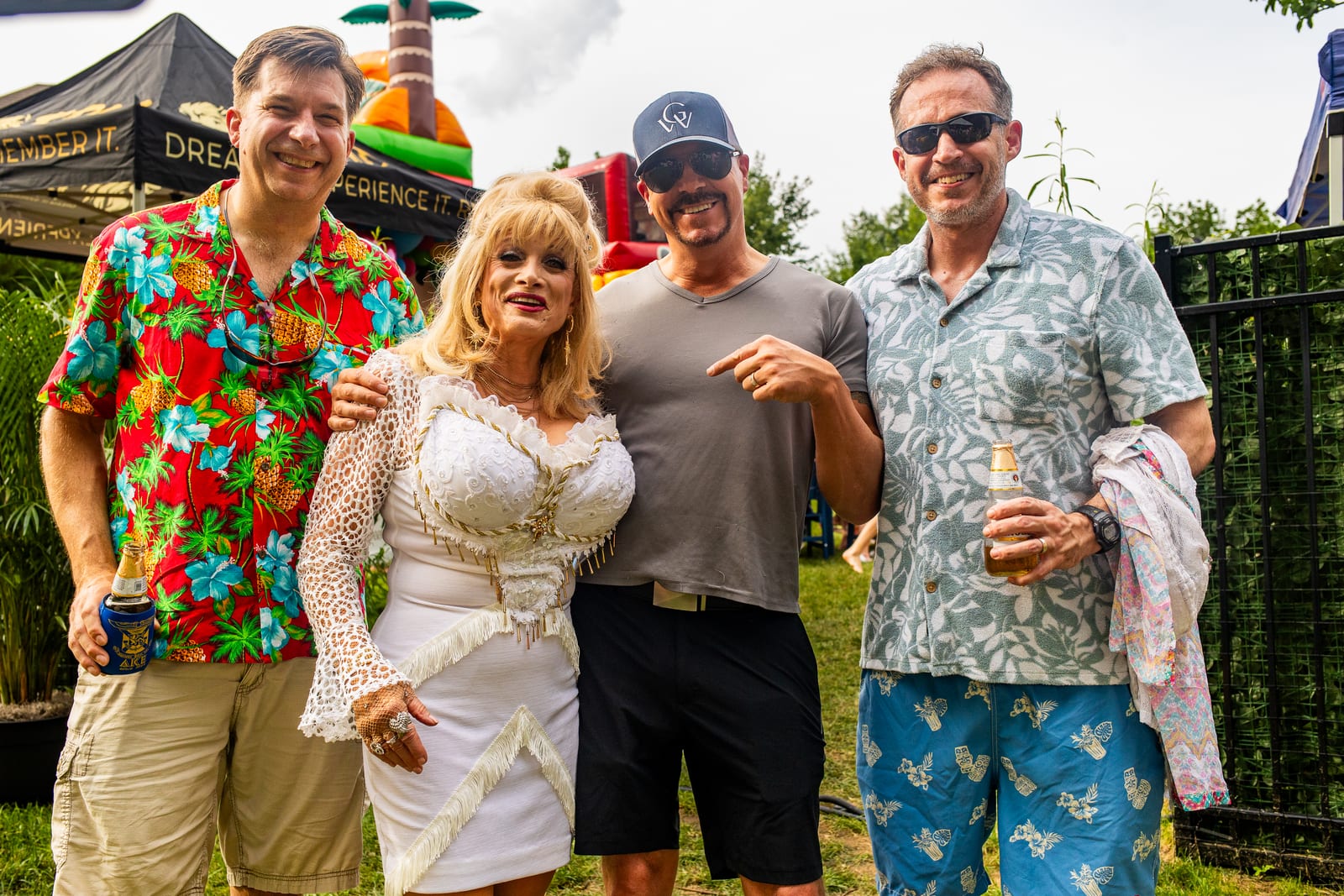 Four guests in tropical shirts posing together at a garden party
