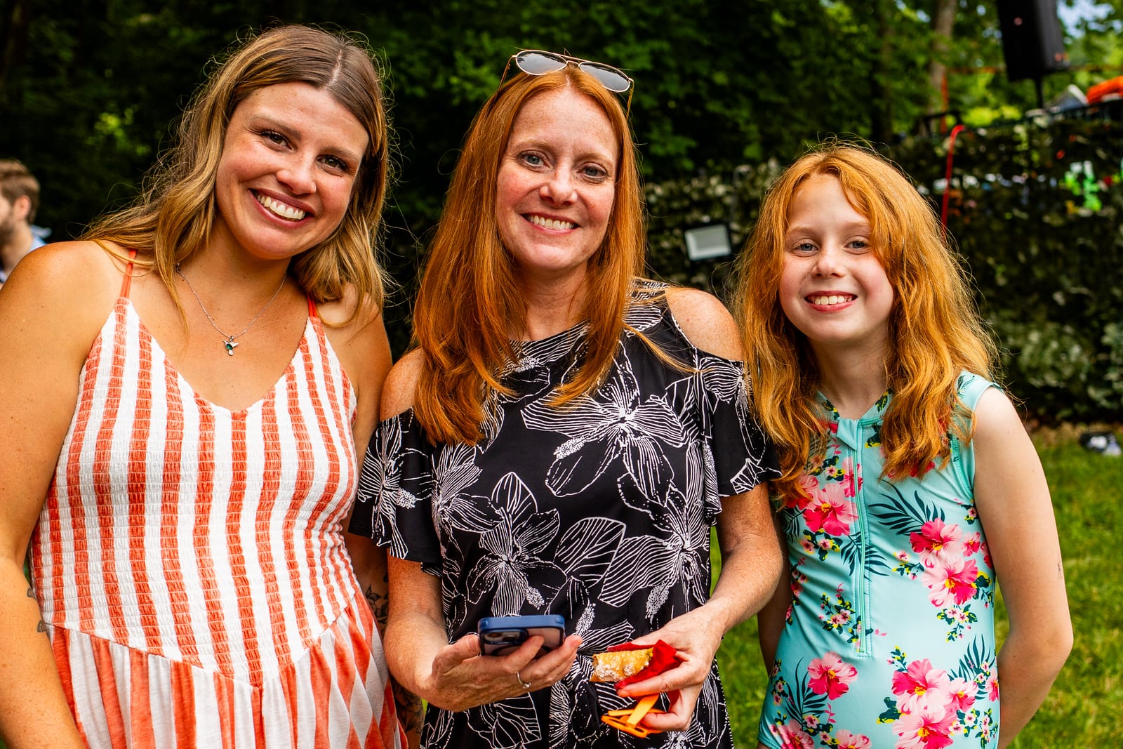 Three guests posing and smiling together at an outdoor celebration