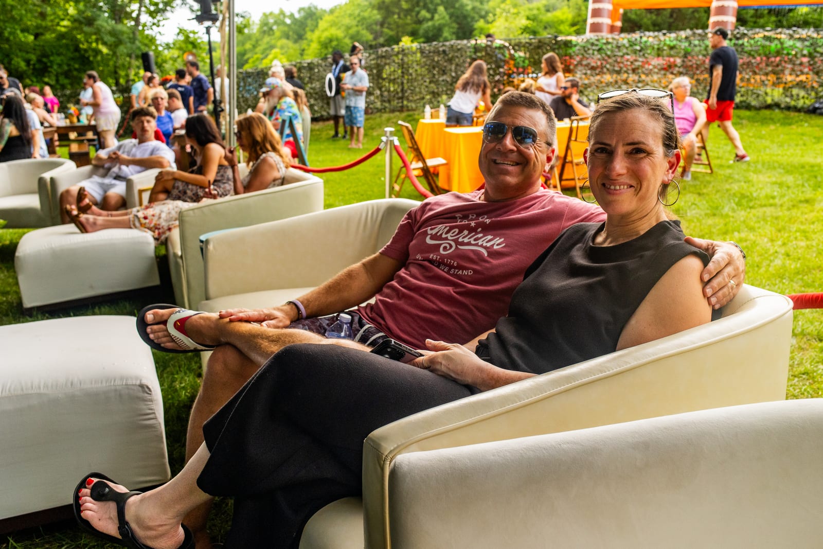 A couple relaxing together on a white lounge sofa at a garden party