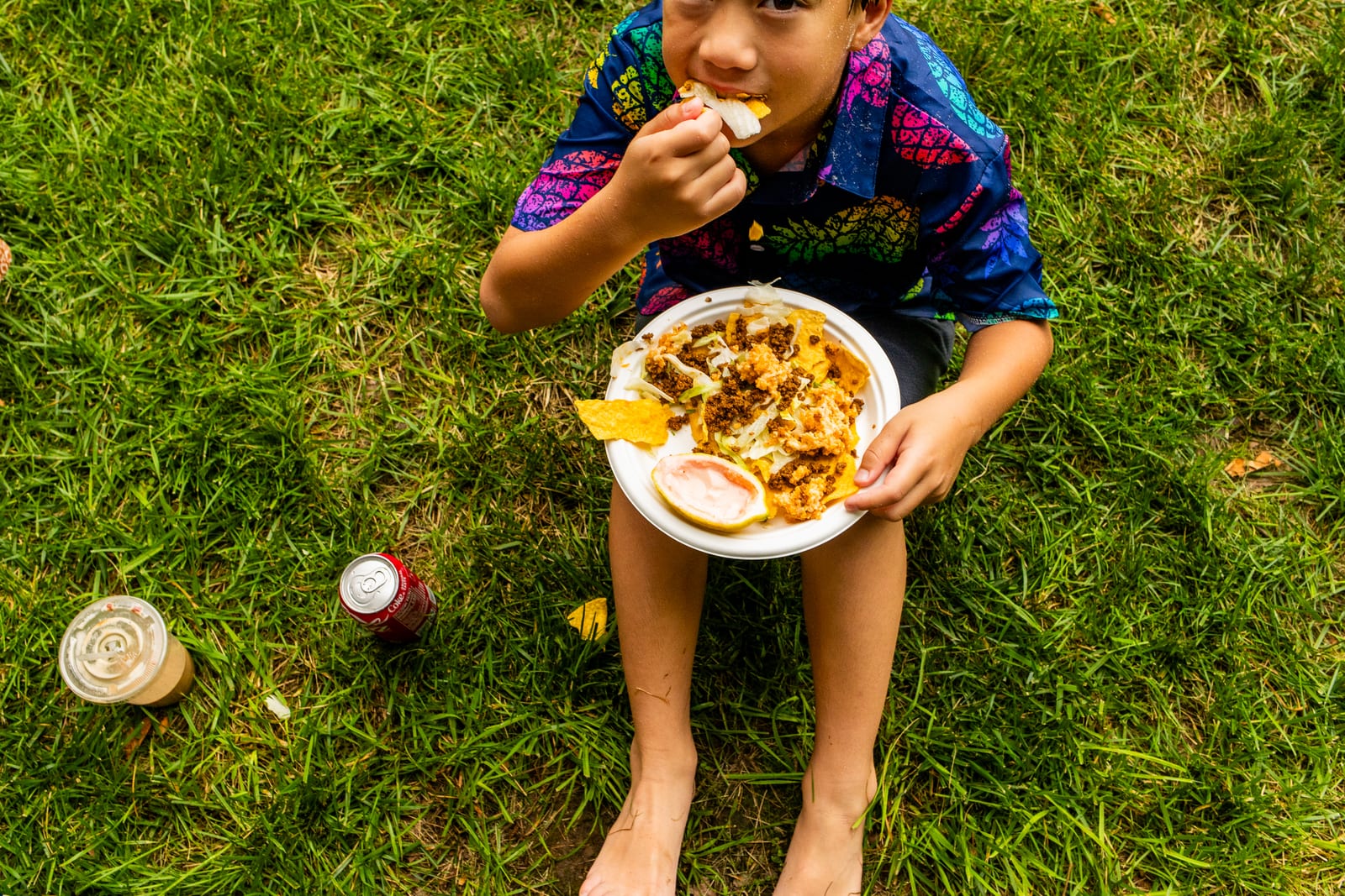 Overhead view of a guest eating from a plate while seated on the grass
